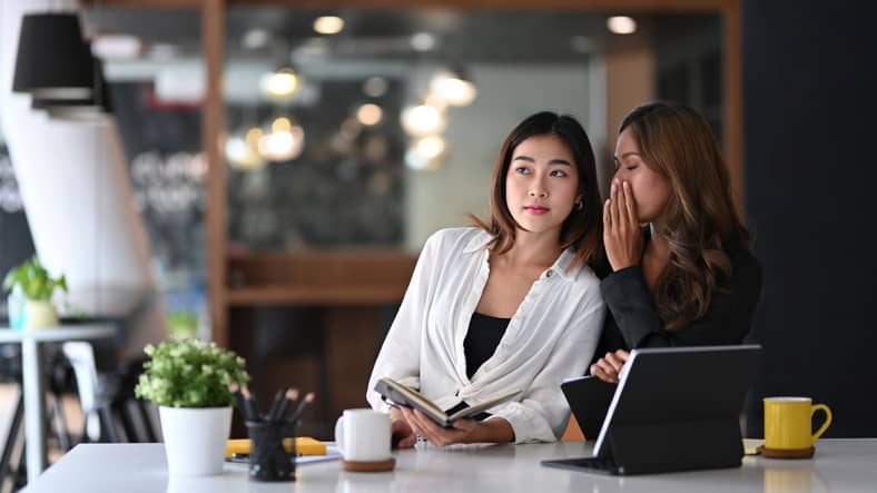 Business woman whispering something in ear of her colleague. Business woman whispering something in ear of her colleague.