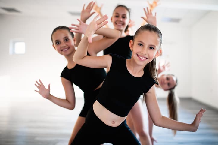 Group of fit happy children exercising ballet in studio together Group of fit children exercising ballet in studio together